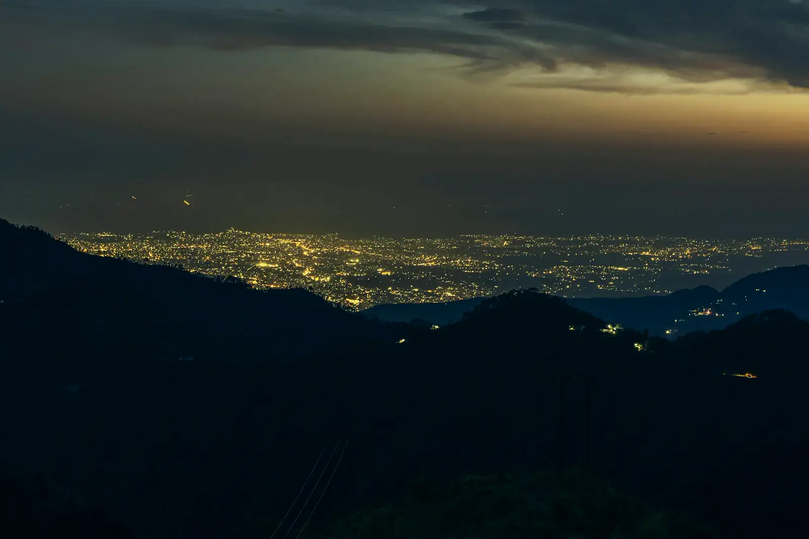 Dehradun's lights spread across the valley at dusk, seen from the Mussoorie ridge.